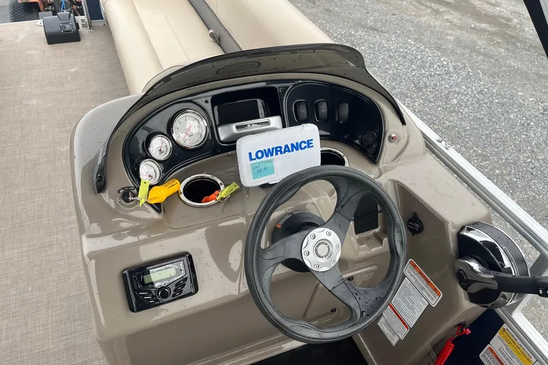 Slide: The Image of 2022 Sun Tracker Party Barge 18 DLX dashboard with steering wheel and Lowrance display. - 2