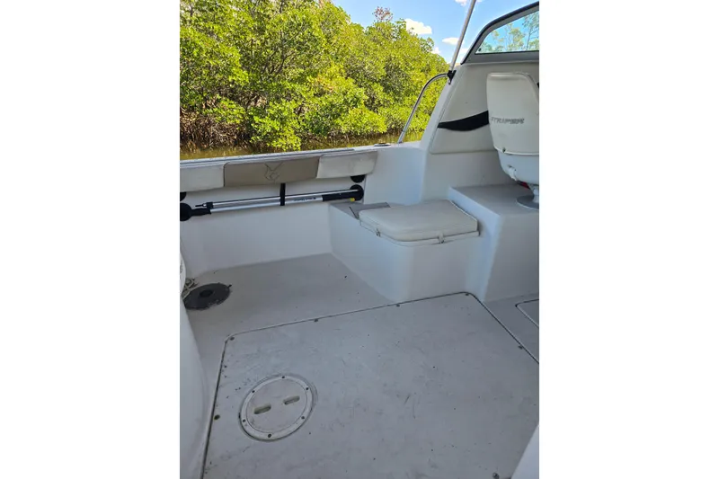 Slide: The Image of 2004 Seaswirl Striper 2101 Walkaround O/B interior with seating and lush greenery background. - 17