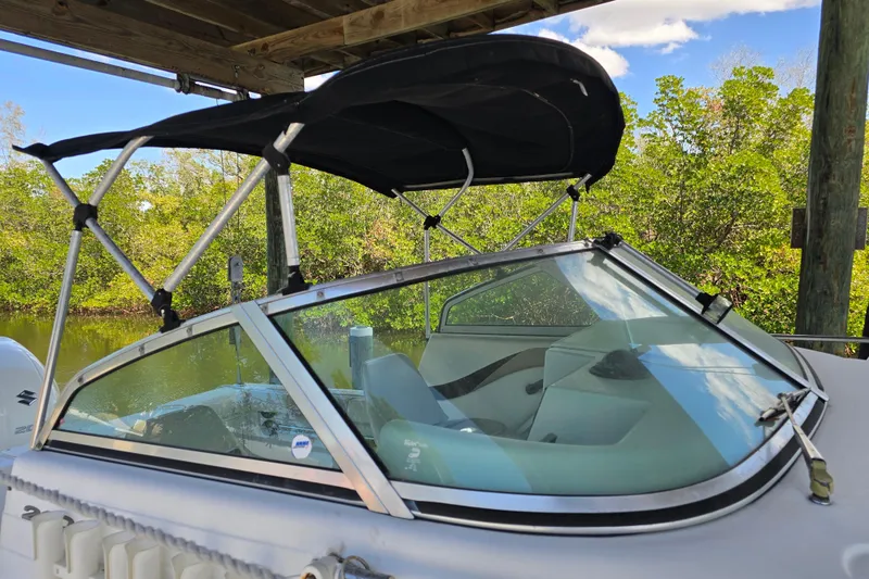 Slide: The Image of 2004 Seaswirl Striper 2101 Walkaround O/B with canopy, docked near lush greenery. - 19