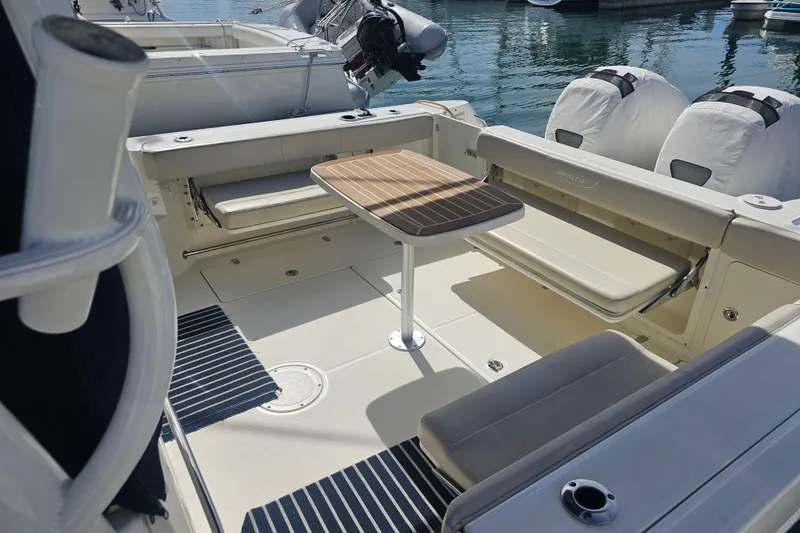 Slide: The Image of 2018 Boston Whaler 315 Conquest boat interior with seating and table, docked at marina. - 22