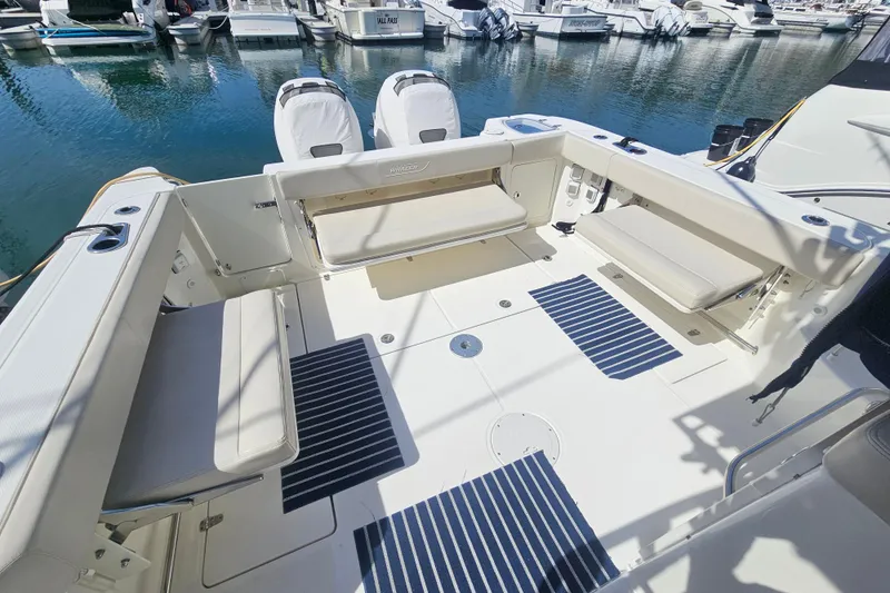 Slide: The Image of 2018 Boston Whaler 315 Conquest boat interior with seating and striped mats at marina. - 23