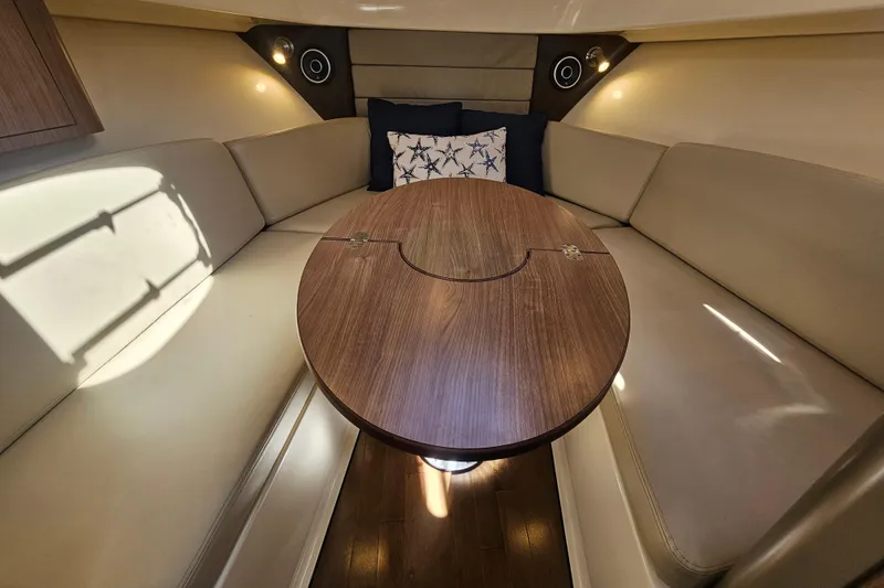 Slide: The Image of 2018 Boston Whaler 315 Conquest cabin interior with cozy seating and wooden table. - 26