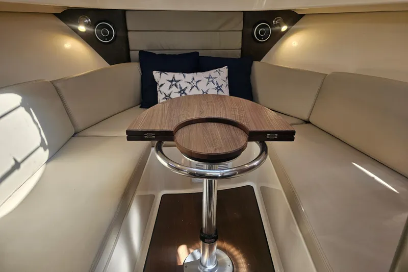 Slide: The Image of 2018 Boston Whaler 315 Conquest cabin interior with beige seating and wooden table. - 27