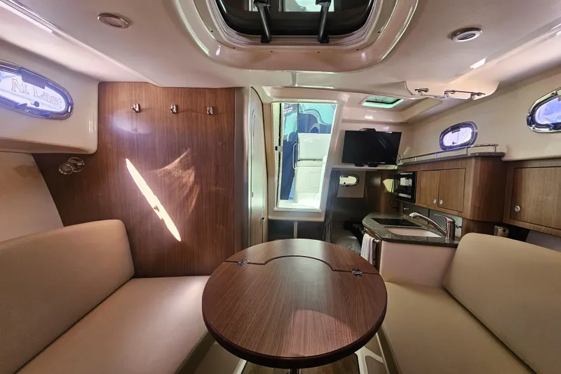 Slide: The Image of 2018 Boston Whaler 315 Conquest cabin interior with seating, table, and kitchenette. - 28