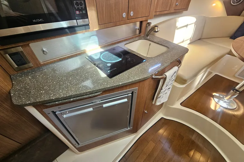 Slide: The Image of 2018 Boston Whaler 315 Conquest interior kitchen with sink, stove, and seating area. - 30