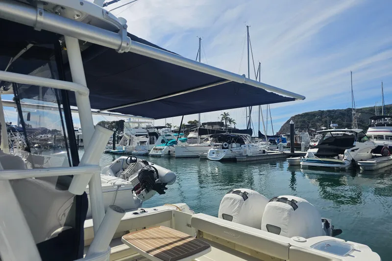 Slide: The Image of 2018 Boston Whaler 315 Conquest docked in a marina, surrounded by various boats. - 6