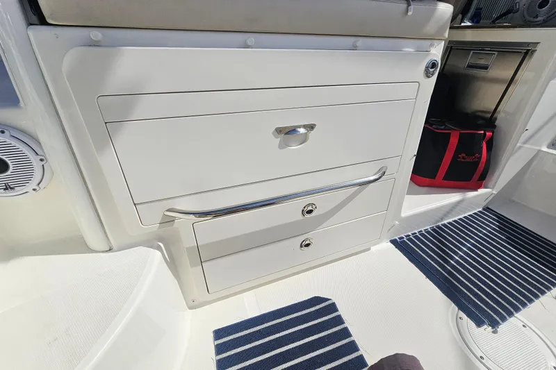 Slide: The Image of 2018 Boston Whaler 315 Conquest interior with storage drawers and striped mats. - 7