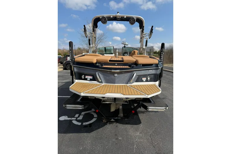Slide: The Image of 2019 MasterCraft XT20 boat, rear view, parked on asphalt with blue sky background. - 10
