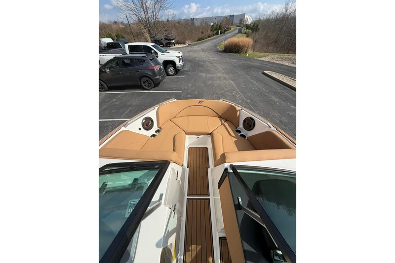 Slide: The Image of 2019 MasterCraft XT20 boat interior with tan seating and wood flooring in a parking lot. - 5
