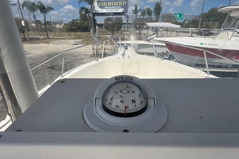 Slide: The Image of Compass view from 1998 Legacy Boat 220 Sea Era, docked with palm trees in background. - 11