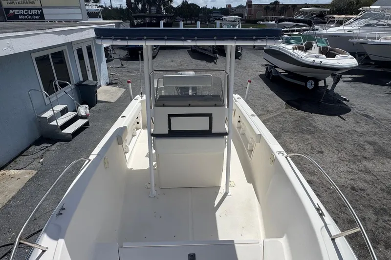 Slide: The Image of 1998 Legacy Boat 220 Sea Era, docked in a marina, showcasing spacious deck and console. - 16