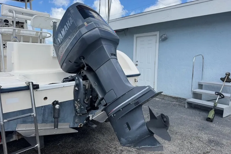 Slide: The Image of 1998 Legacy Boat 220 Sea Era with Yamaha outboard motor, parked near a blue building. - 29