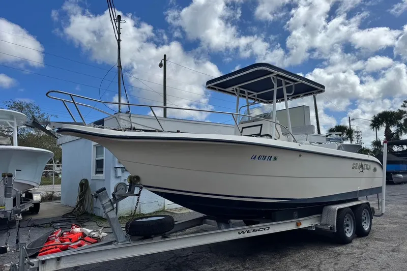 Slide: The Image of 1998 Legacy Boat 220 Sea Era on trailer under cloudy sky. - 3