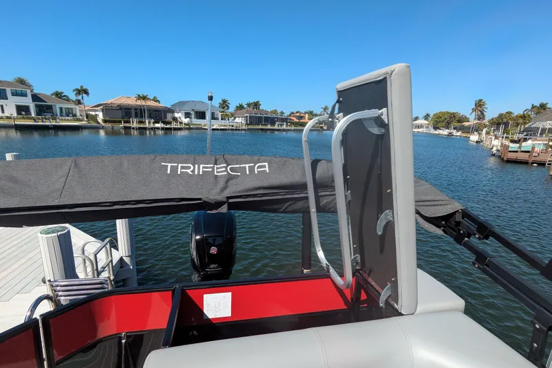 Slide: The Image of 2023 Trifecta 20CC 2.75 pontoon boat docked by waterfront homes. - 10