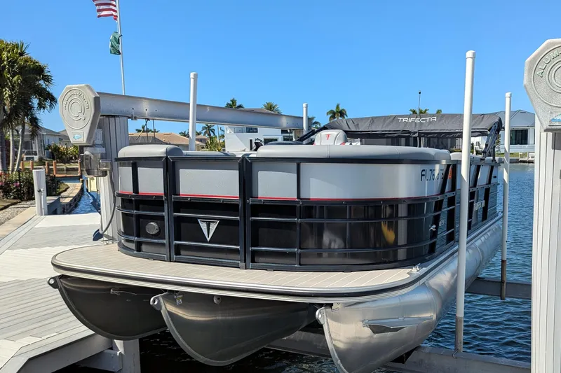 Slide: The Image of 2023 Trifecta 20CC 2.75 pontoon boat docked on a sunny day. - 13
