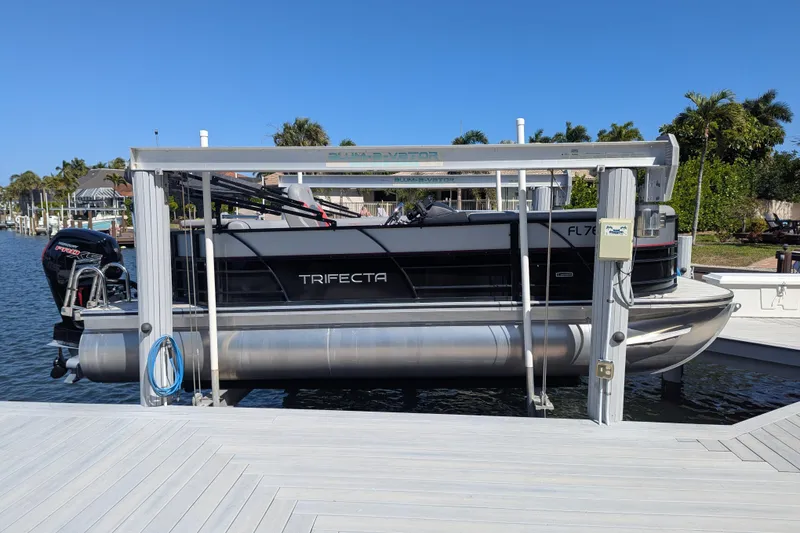 Slide: The Image of 2023 Trifecta 20CC 2.75 pontoon boat on lift at marina dock. - 16