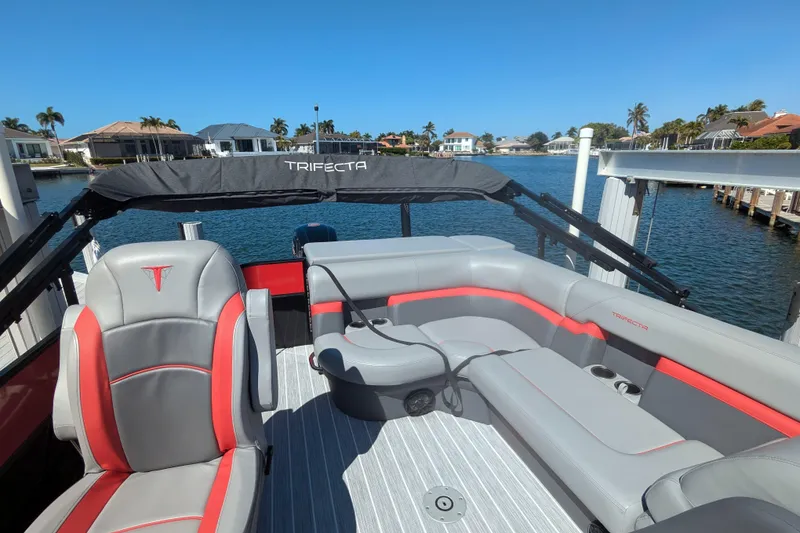 Slide: The Image of 2023 Trifecta 20CC 2.75 pontoon boat with stylish seating on a sunny waterfront. - 6