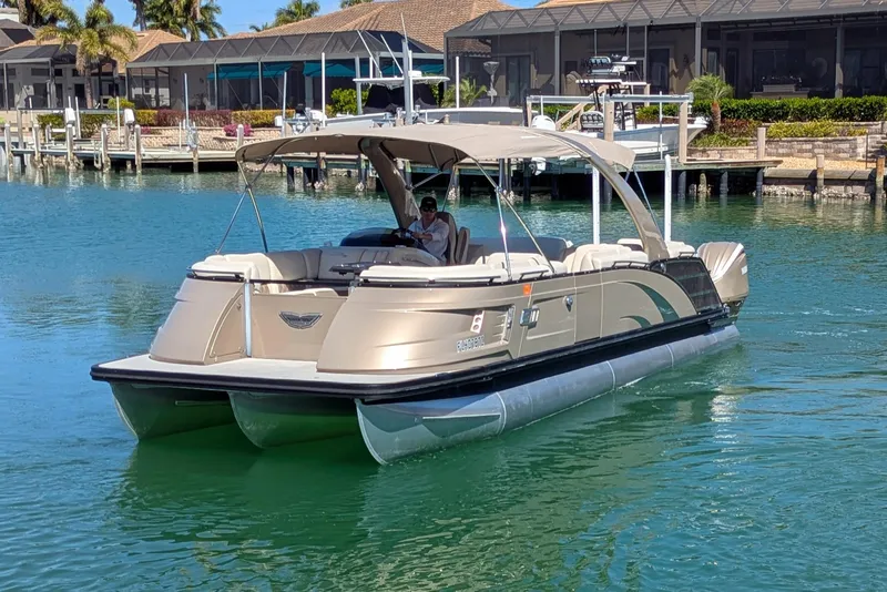 Slide: The Image of 2022 Bennington QXFBAX2 pontoon boat cruising on a sunny waterfront. - 2