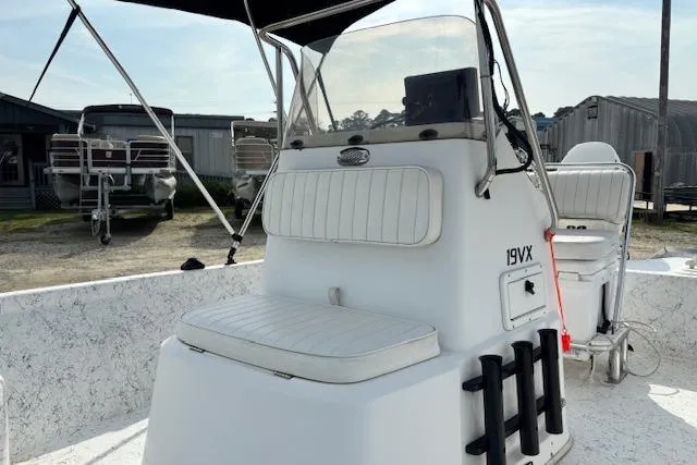 Slide: The Image of 2009 Kenner 19VX boat interior with white seating and console, parked outdoors. - 23