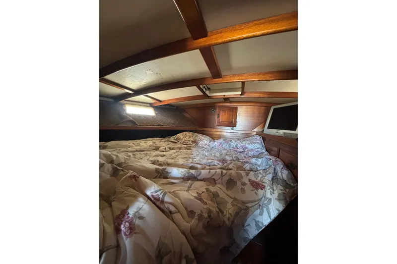 Slide: The Image of 1973 Luhrs 290 Sport Fisherman cabin interior with floral bedding and wooden accents. - 9