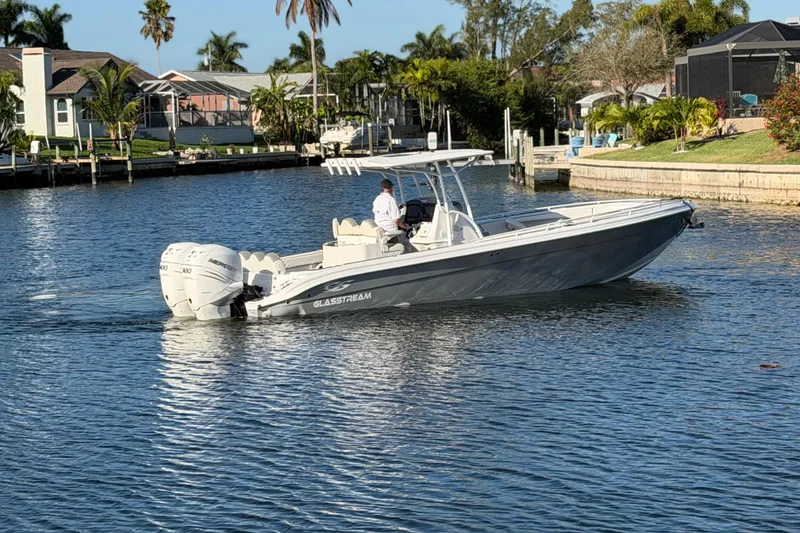 Slide: The Image of 2022 Glasstream 328 Pro-XS boat cruising on a sunny waterfront. - 4