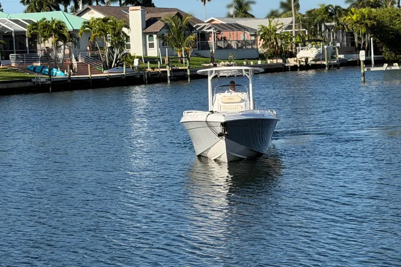 Slide: The Image of 2022 Glasstream 328 Pro-XS boat cruising on a sunny waterfront near residential homes. - 7