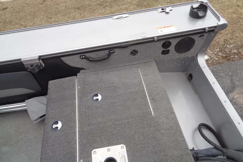 Slide: The Image of 2016 Lund 2175 Pro-V boat interior with carpeted deck and storage compartments. - 13