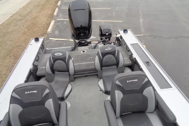 Slide: The Image of 2016 Lund 2175 Pro-V boat interior with seating and motor, parked on asphalt. - 16