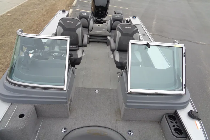 Slide: The Image of 2016 Lund 2175 Pro-V boat interior with seating and windshield, parked on pavement. - 19