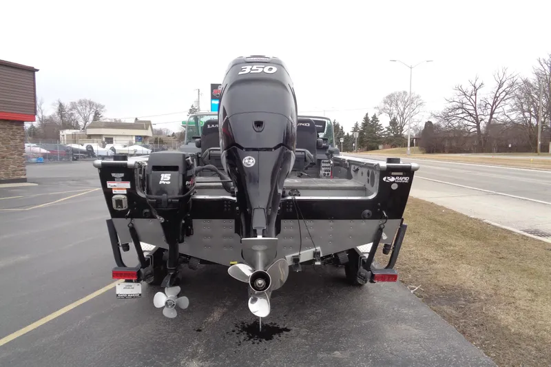 Slide: The Image of 2016 Lund 2175 Pro-V boat with powerful outboard motors, parked on a roadside. - 3