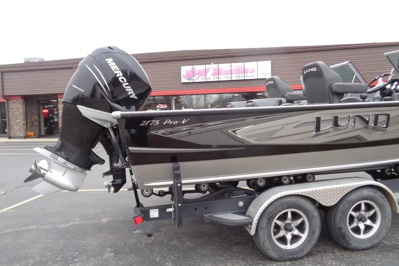 Slide: The Image of 2016 Lund 2175 Pro-V boat with Mercury engine on trailer, parked outside a store. - 5