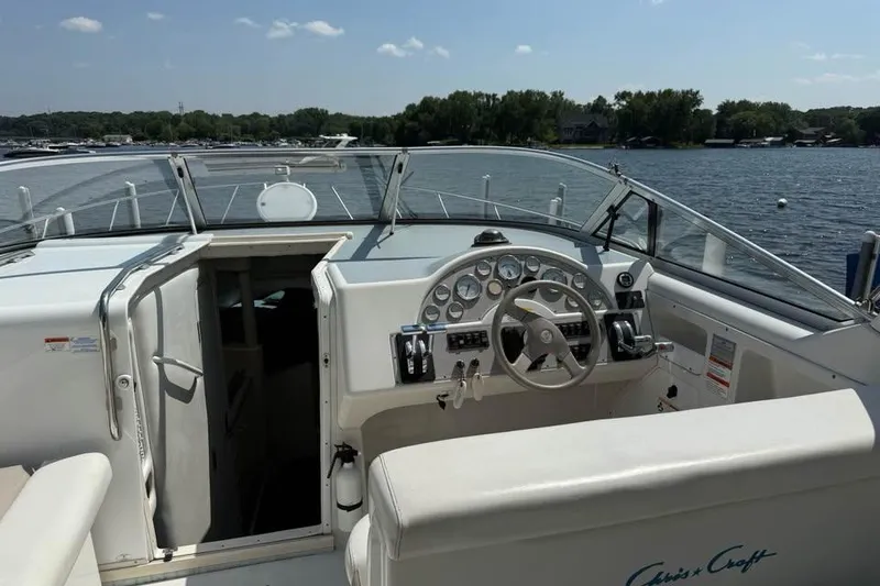 Slide: The Image of 1995 Chris Craft 34 Crowne boat cockpit with steering wheel and dashboard, on a sunny lake. - 4