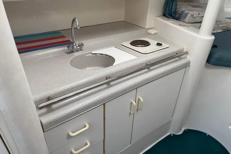 Slide: The Image of Compact kitchen area in a 1995 Chris Craft 34 Crowne boat, featuring a sink and stove. - 7