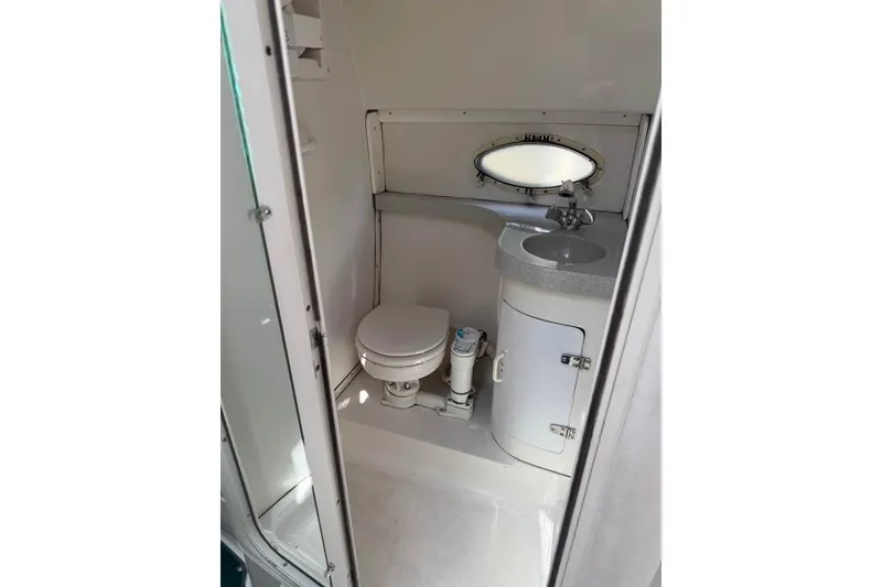 Slide: The Image of 1995 Chris Craft 34 Crowne boat bathroom with toilet, sink, and oval window. - 8