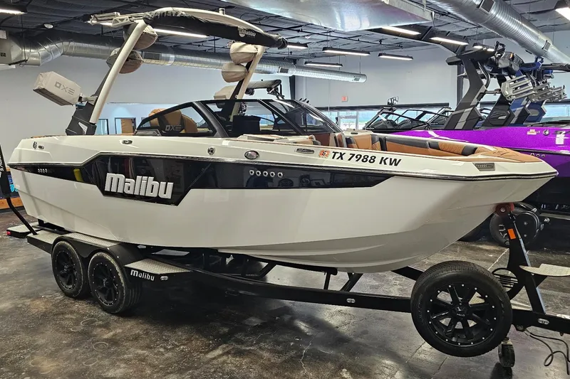Slide: The Image of 2023 Malibu M220 boat on trailer in showroom, featuring sleek design and modern features. - 18