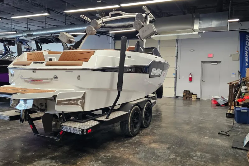 Slide: The Image of 2023 Malibu M220 boat on trailer in showroom, featuring sleek design and modern amenities. - 20