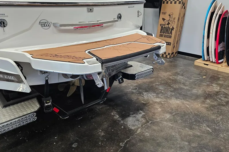 Slide: The Image of 2023 Malibu M220 boat rear view with surfboards and surf accessories in a garage. - 22