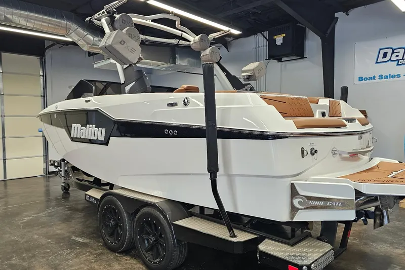 Slide: The Image of 2023 Malibu M220 boat on trailer in showroom, featuring sleek design and modern amenities. - 25
