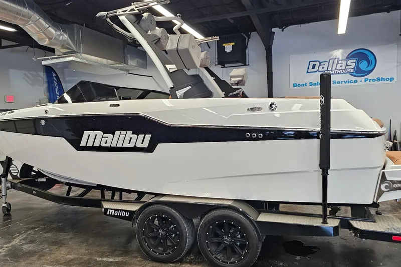 Slide: The Image of 2023 Malibu M220 boat displayed indoors on a trailer at Dallas Boathouse. - 26