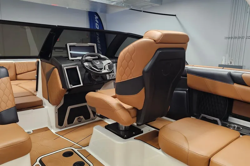 Slide: The Image of 2023 Malibu M220 boat interior with luxurious tan and black seating and modern dashboard. - 8