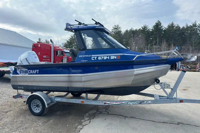 The Image of 2021 Stabicraft 1850 SuperCab boat on trailer, blue and silver design, parked outdoors. - 0
