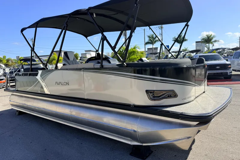 Slide: The Image of 2026 Avalon 2585 LSZ Quad Lounger Tri Toon boat with canopy, parked outdoors. - 6