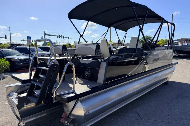 Slide: The Image of 2026 Avalon 2585 LSZ Quad Lounger Tri Toon boat with black canopy in parking lot. - 7