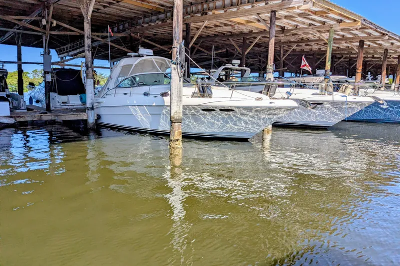 Slide: The Image of 2002 Sea Ray 340 Sundancer docked in a marina under a wooden shelter. - 146