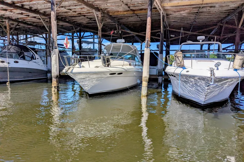 Slide: The Image of 2002 Sea Ray 340 Sundancer docked in a marina under a wooden shelter. - 2