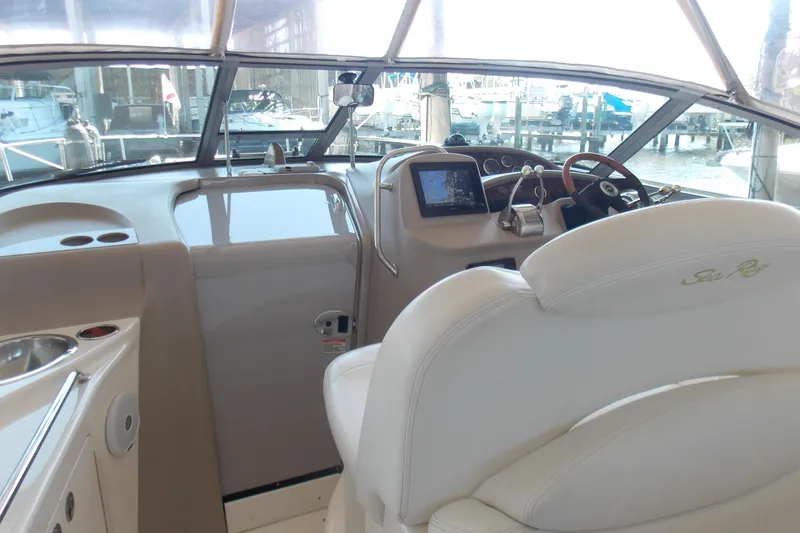 Slide: The Image of 2002 Sea Ray 340 Sundancer helm with steering wheel, navigation system, and white seating. - 4