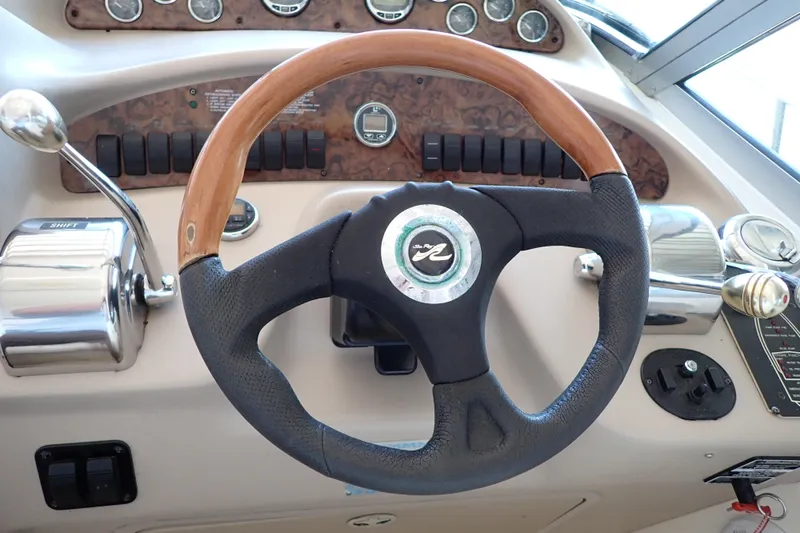 Slide: The Image of Steering wheel of a 2002 Sea Ray 340 Sundancer boat, featuring wood and leather accents. - 44