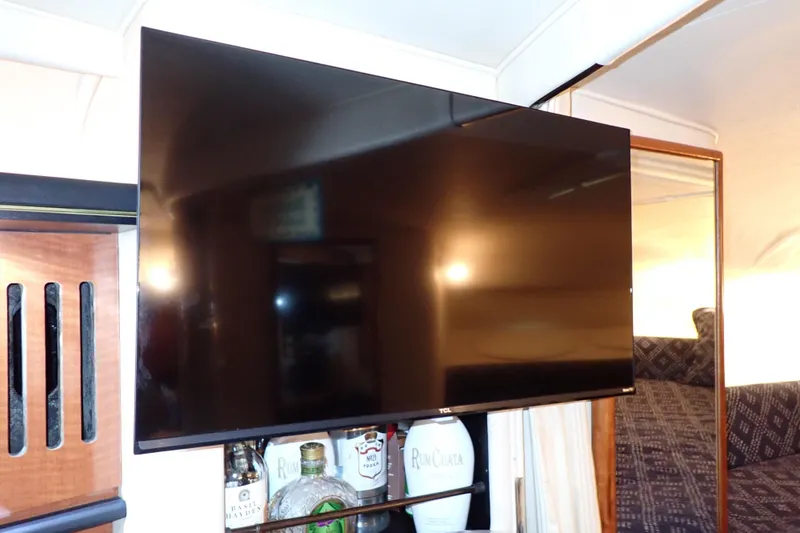 Slide: The Image of Flat-screen TV in 2002 Sea Ray 340 Sundancer cabin with liquor bottles below. - 72