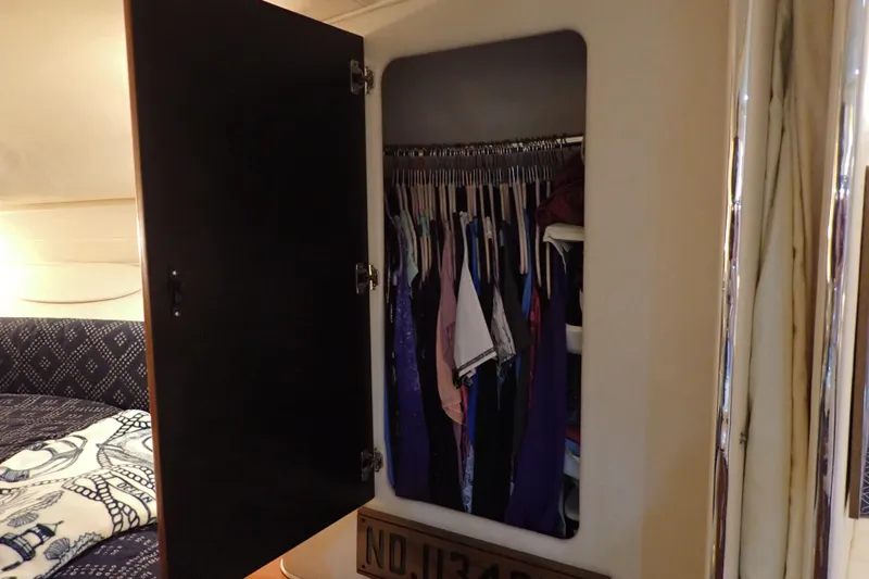 Slide: The Image of Open closet with clothes inside a 2002 Sea Ray 340 Sundancer boat cabin. - 92