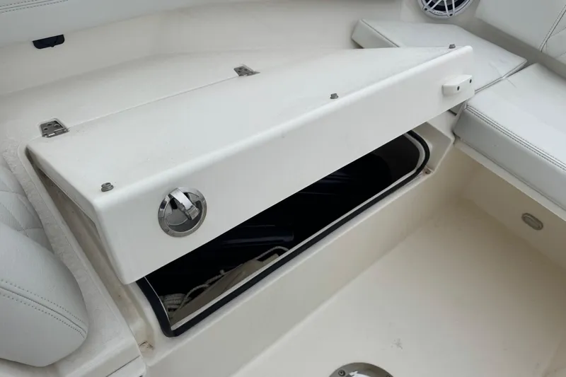 Slide: The Image of 2024 Cobia 240 Dual Console boat storage compartment with open lid. - 16